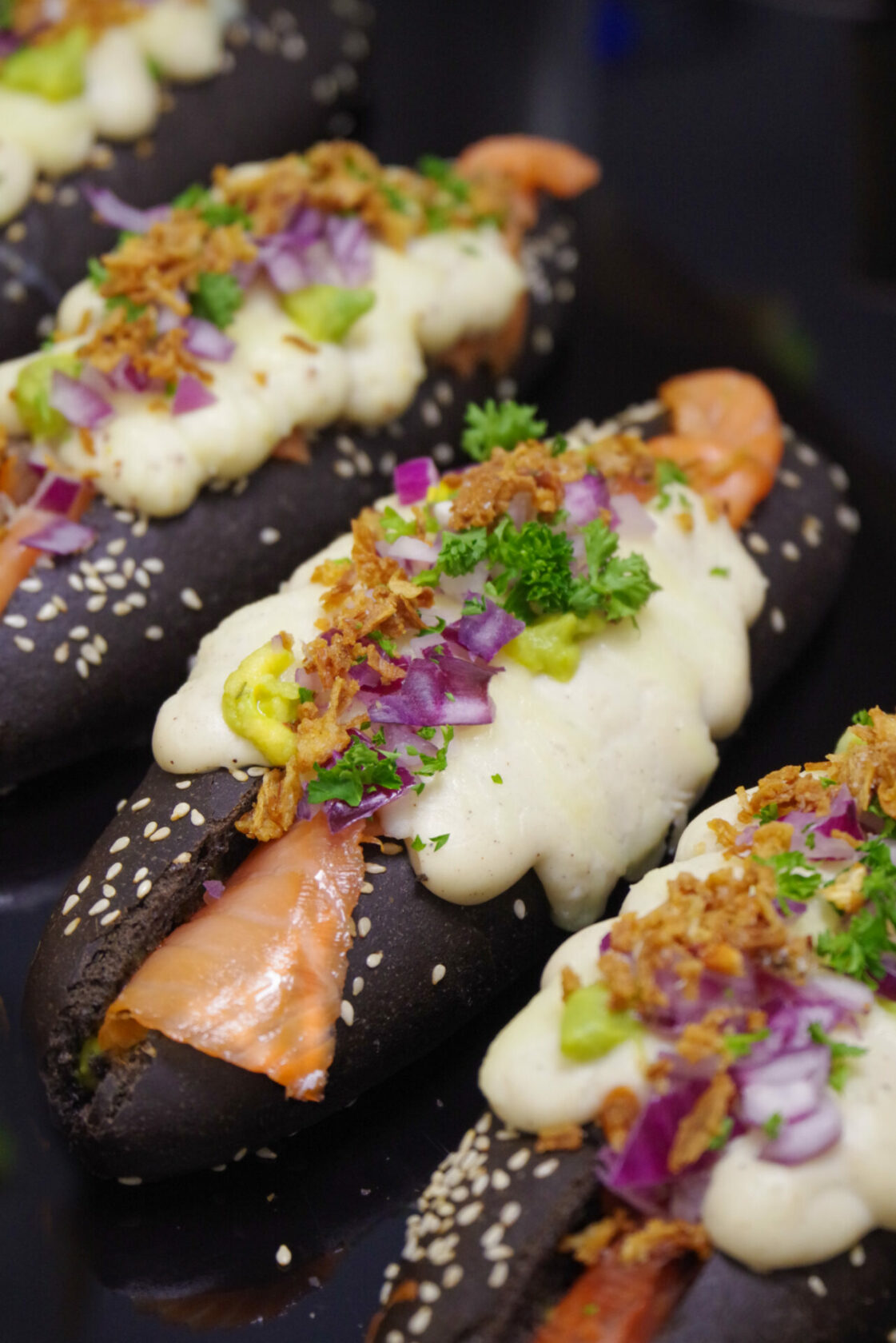 Hot dog original dans un pain noir avec une béchamel et des crispy oignons lors de la formation snacking avec Peyo Nobre